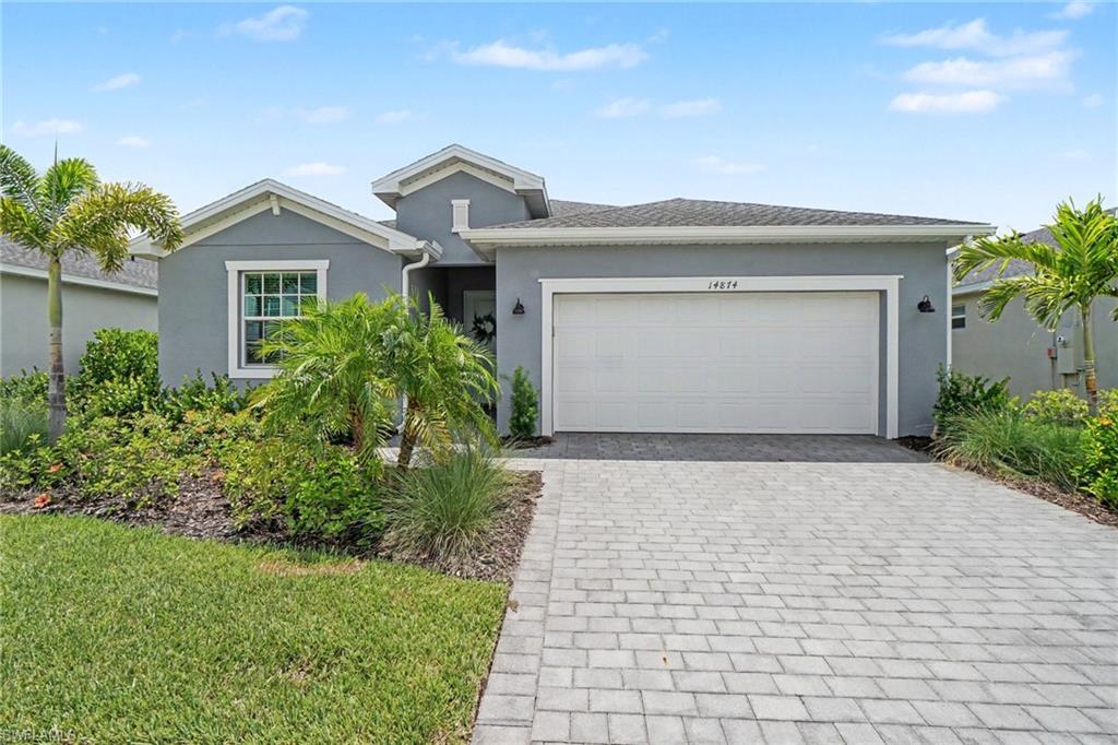 Contemporary single-story residence featuring a two-car garage, paver driveway, and a well-maintained lawn