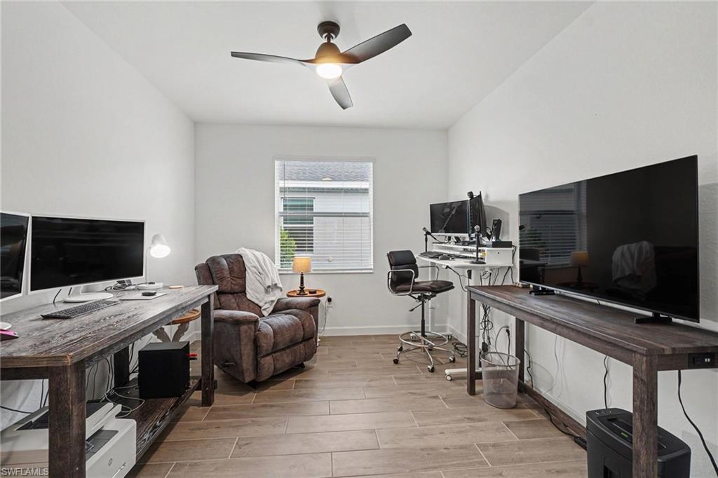 Room featuring wood-look tile flooring, white painted walls, and a ceiling fan with integrated lighting