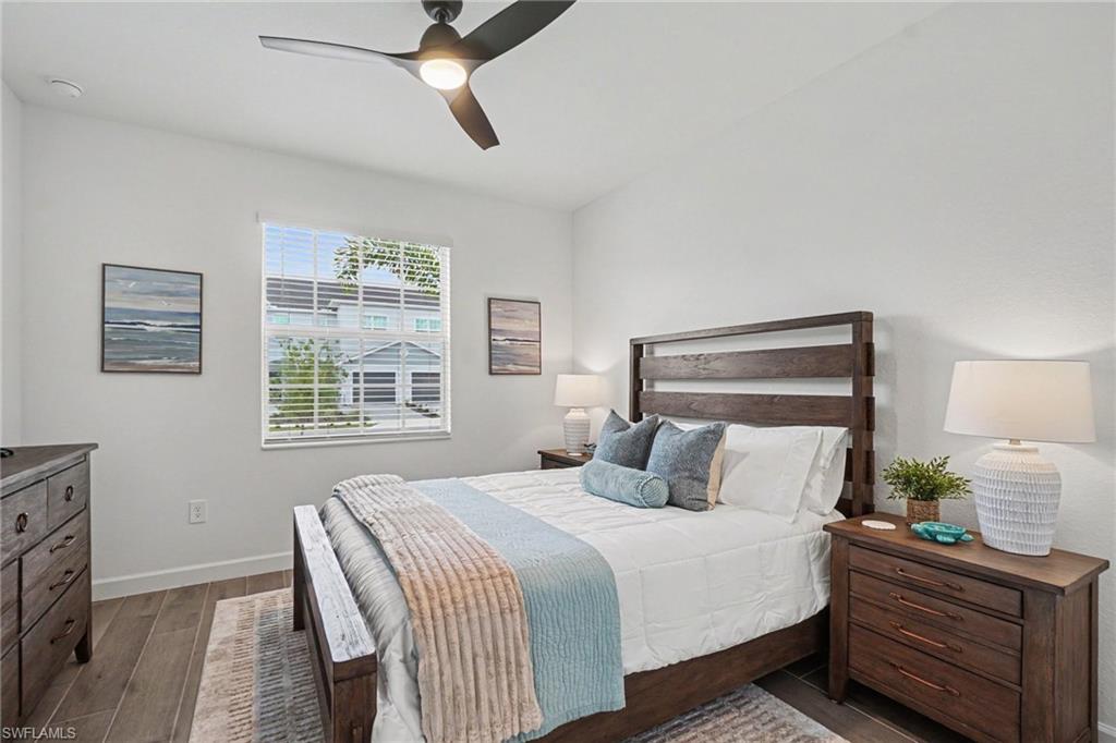 Bedroom featuring wood-finish flooring, a contemporary ceiling fan with integrated lighting, and a white framed window with blinds