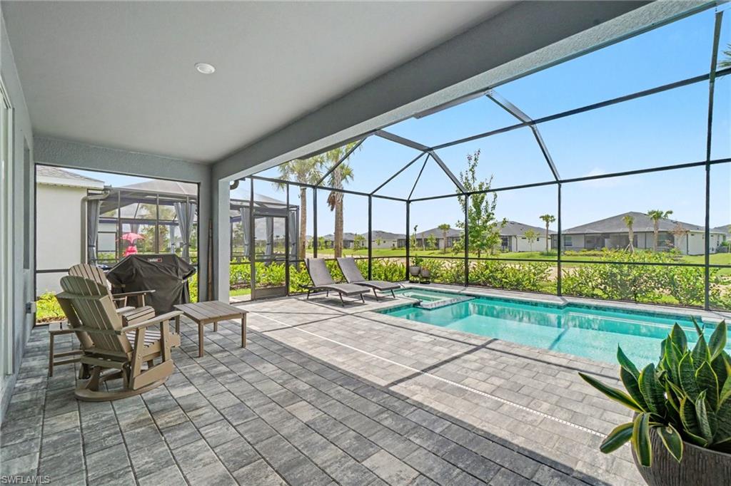 Screened lanai featuring a swimming pool, integrated spa, and paver flooring