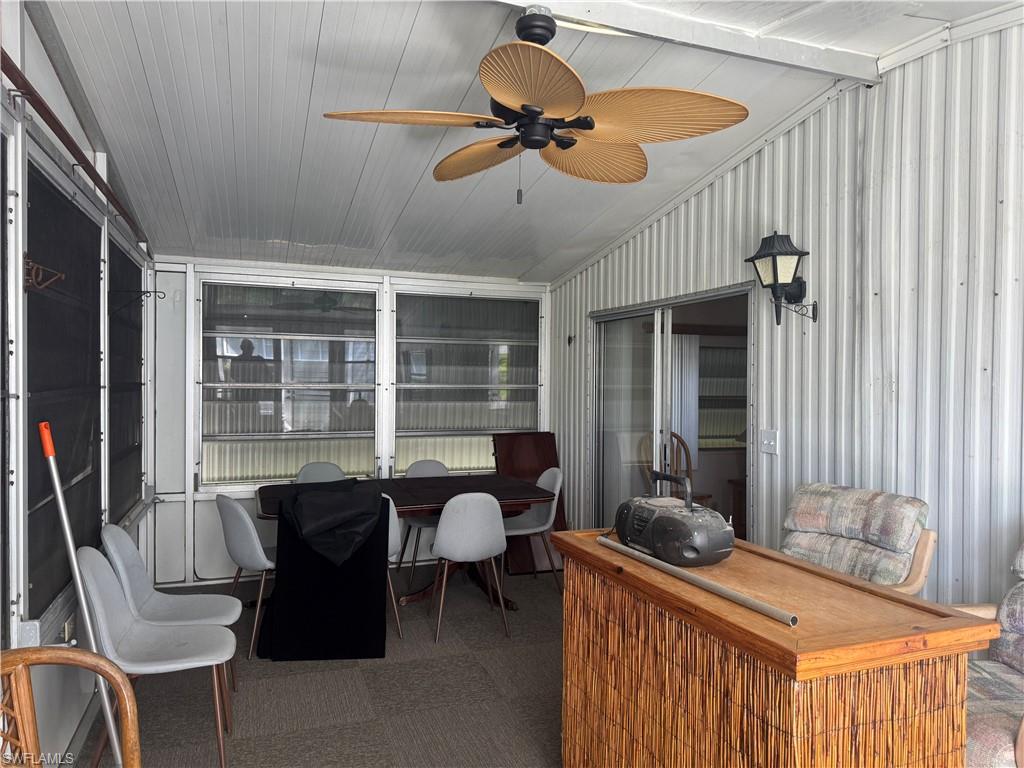 Screened-in porch featuring a ceiling fan, wall-mounted light fixture, sliding glass door, and a textured wall finish