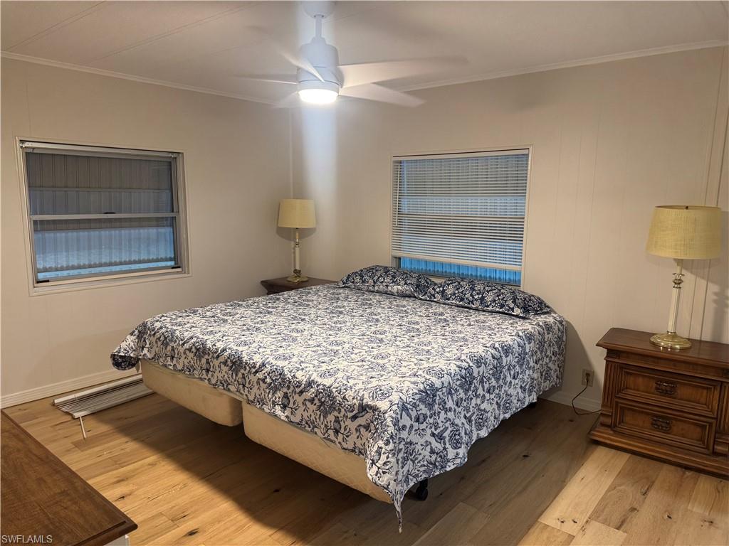 Room featuring wood-finish flooring, two windows with blinds, and a ceiling fan with integrated lighting
