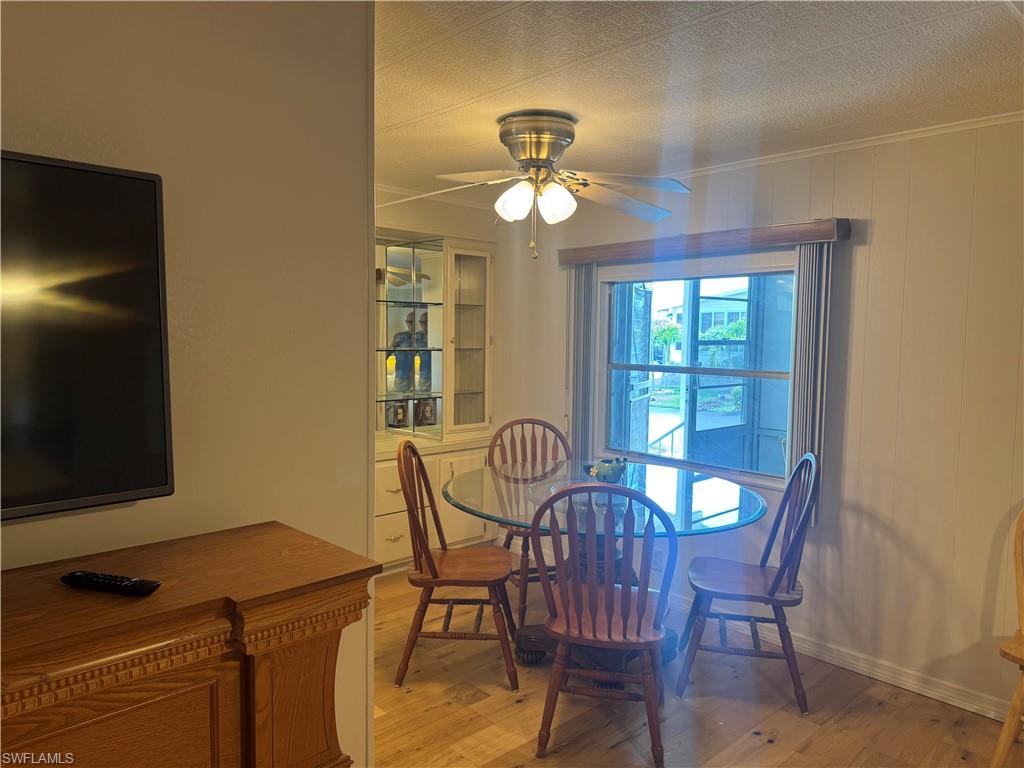 Dining area featuring wood-finish flooring, a ceiling fan with integrated lighting, and a prominent window