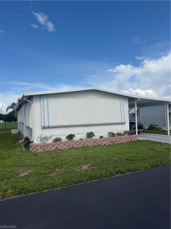 White exterior siding with blue striped awnings, an attached carport, and a decorative brick-lined planting bed