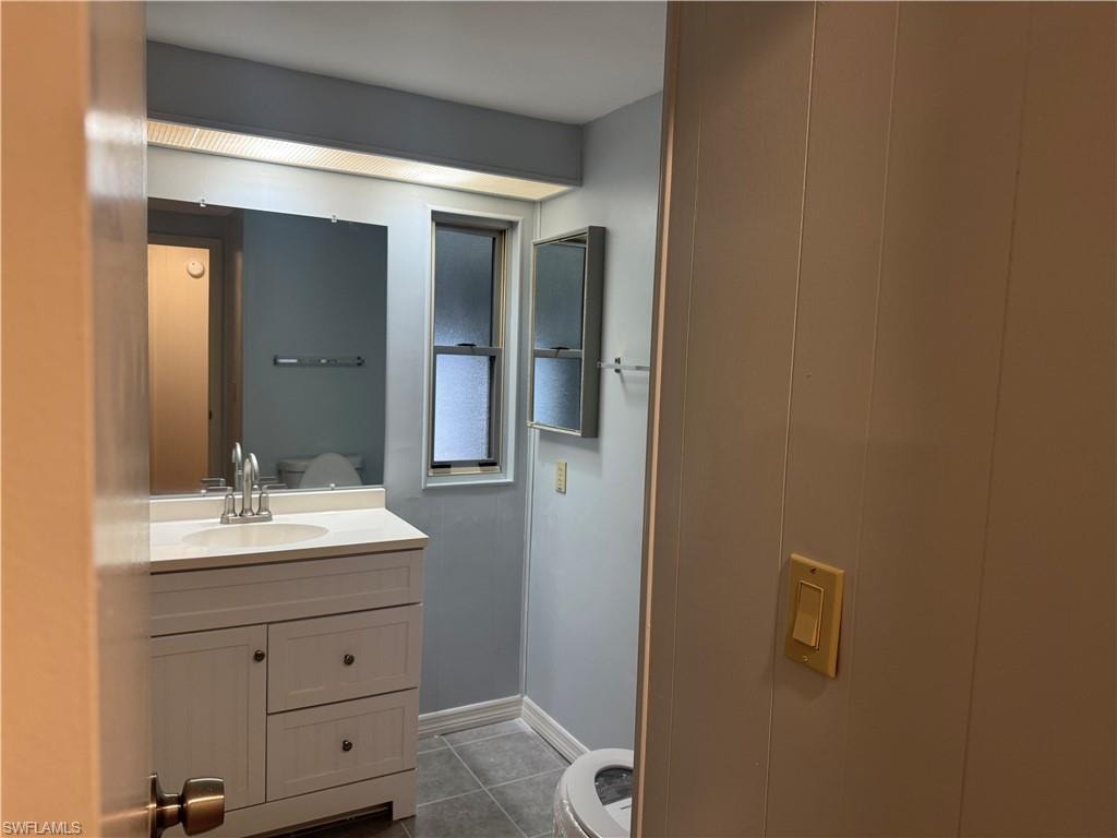 Bathroom featuring a white vanity with an integrated sink, polished chrome faucet, and a wall-mounted mirror