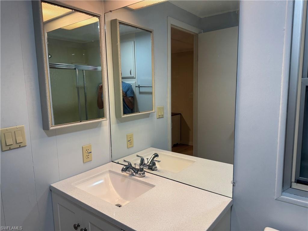 Bathroom featuring a white vanity with an integrated sink, a speckled countertop, and a chrome faucet