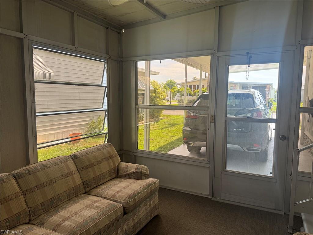 Screened enclosure featuring jalousie windows, a full-view screen door, aluminum framing, and a hard surface floor