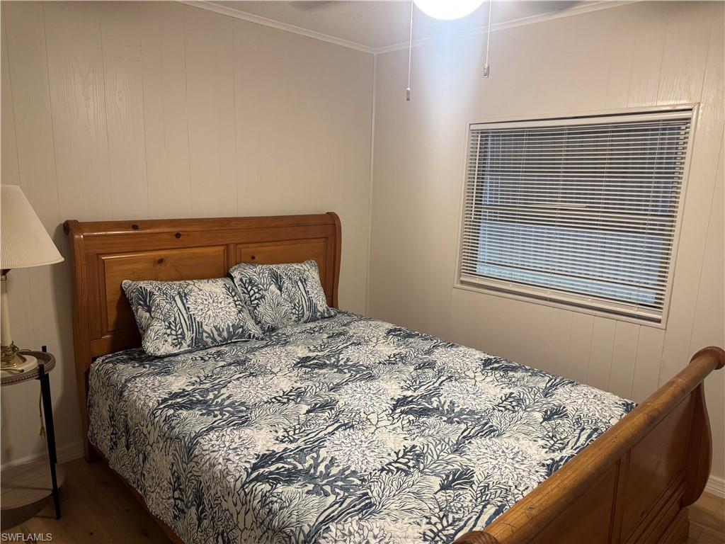 Bedroom featuring wood-finish paneling, a single window with blinds, and wood-finish flooring