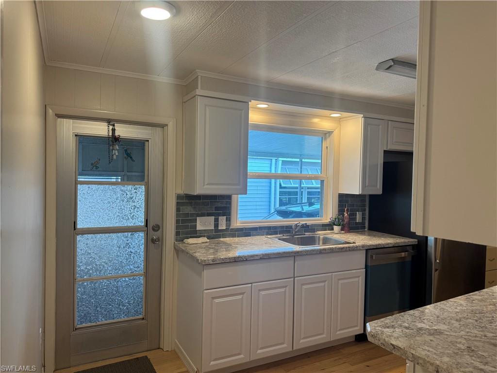 Kitchen featuring white shaker-style cabinetry, granite-finish countertops, stainless steel sink, and a tiled backsplash