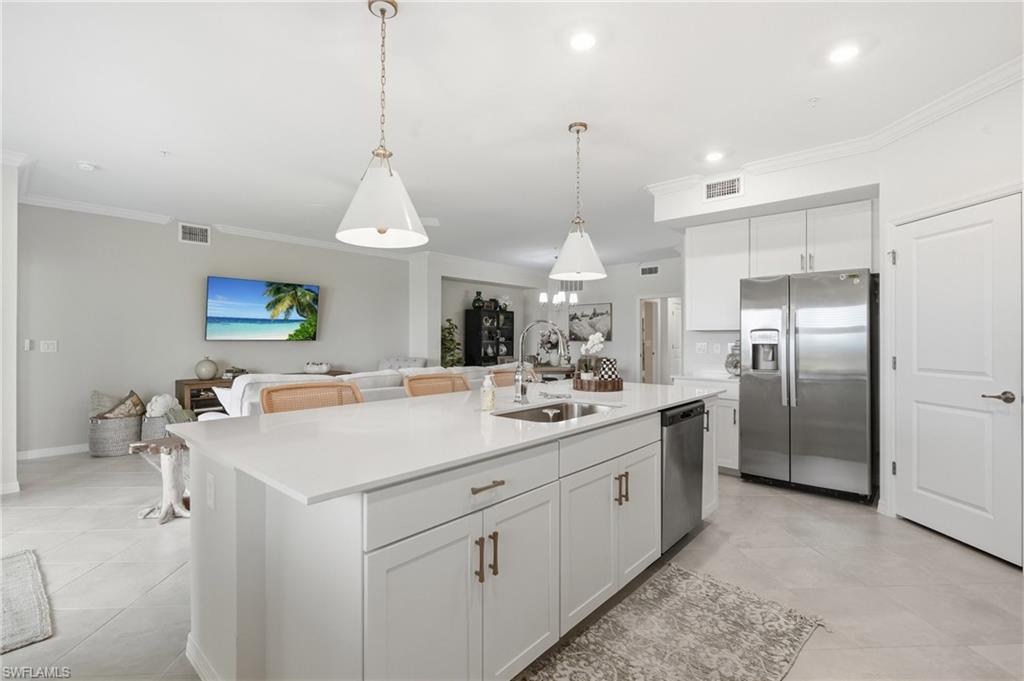 Spacious kitchen island featuring a quartz countertop, integrated sink, and pendant lighting