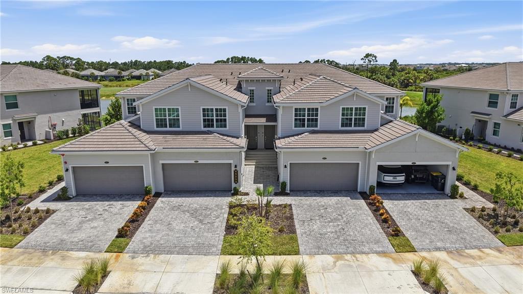 Modern multi-unit residence featuring light gray siding, tiled roofing, and paver driveways