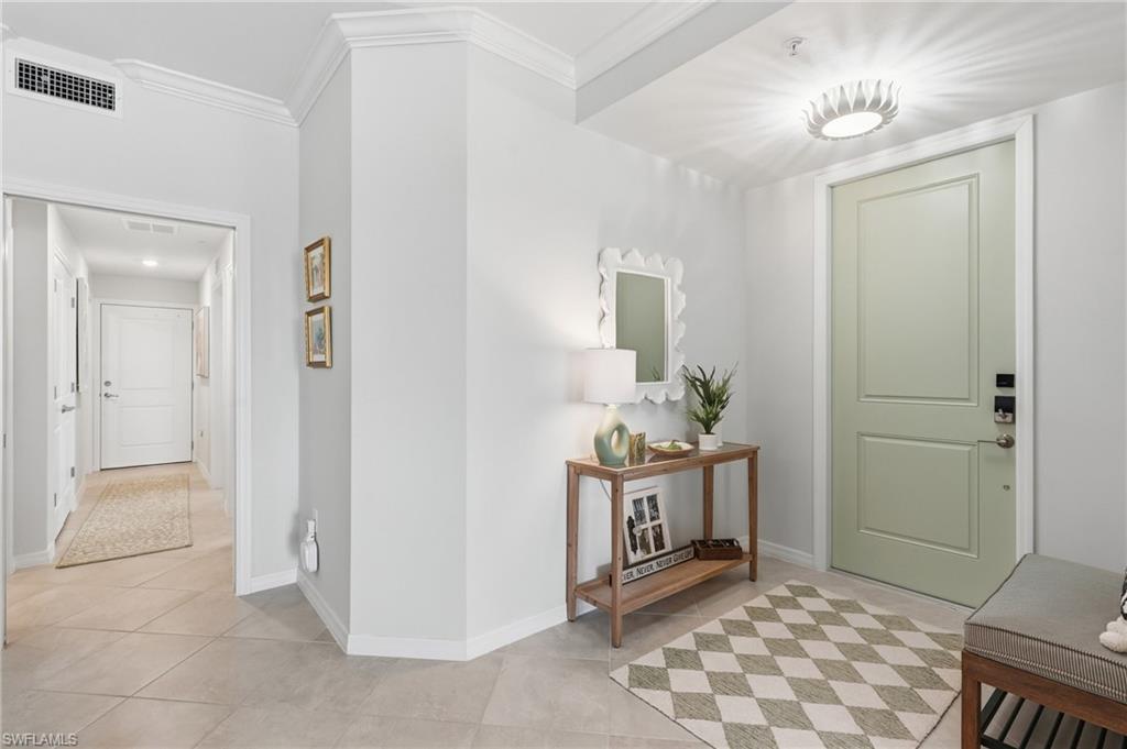 Entry foyer featuring a paneled door, crown molding, and large format tile flooring