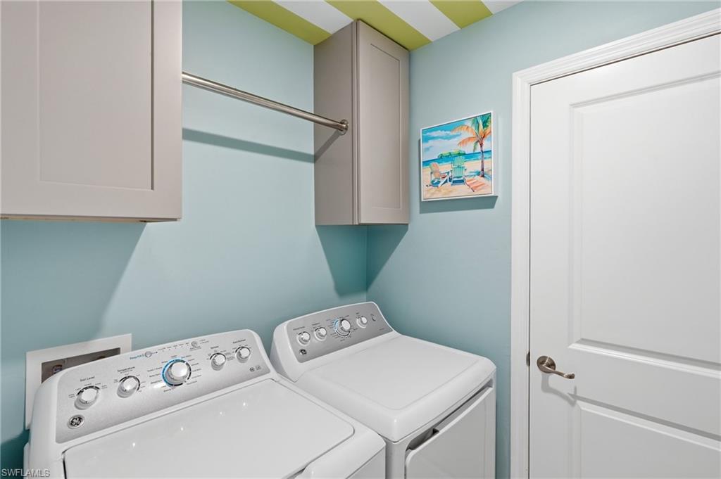 Dedicated laundry space featuring built-in cabinetry, a chrome hanging rod, and light blue wall paint