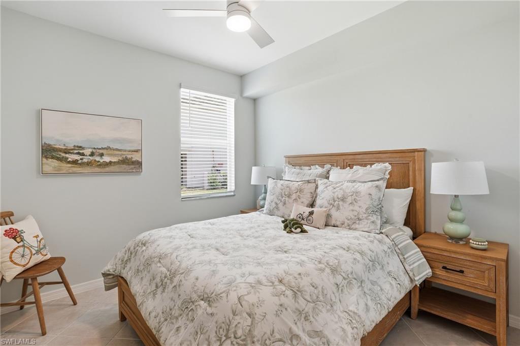 Bedroom featuring light-toned wall paint, a built-in ceiling fan with integrated lighting, a single window with blinds, and tile flooring