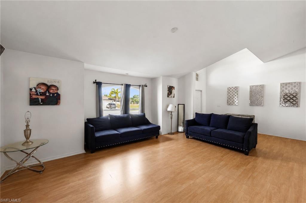 Bright living area featuring wood-finish flooring, vaulted ceilings, and ample natural light from multiple windows