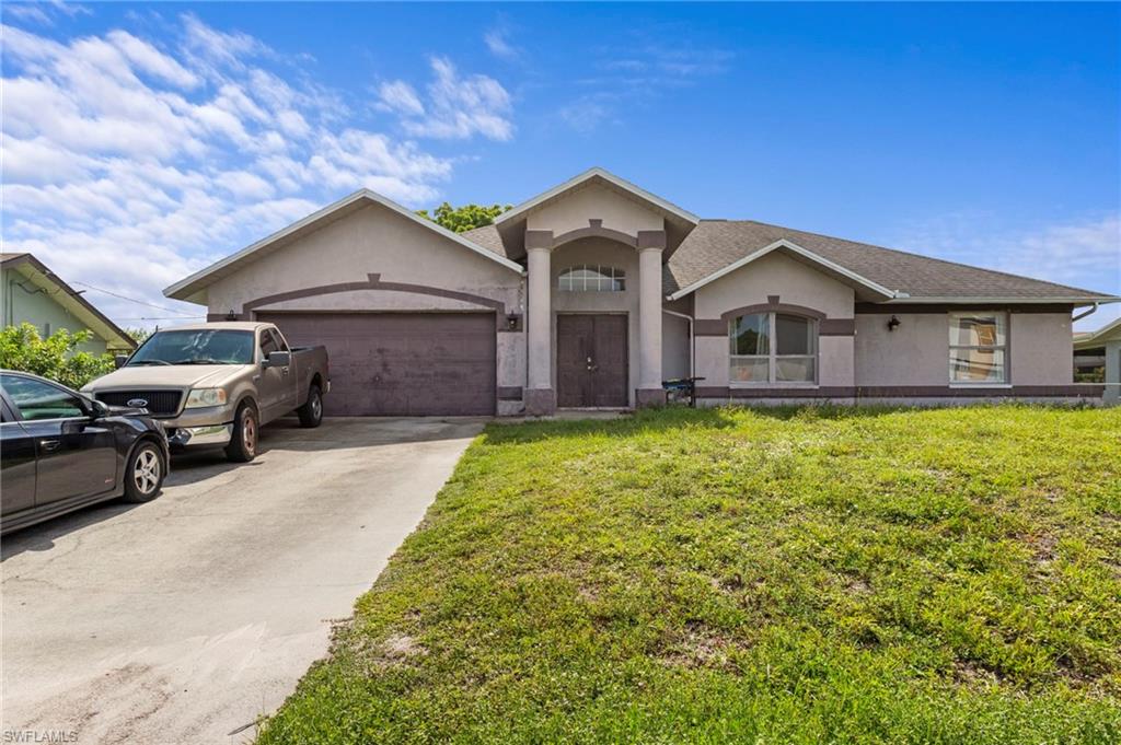 Single-story stucco residence featuring a dual-car garage, arched entry portico, and a concrete driveway