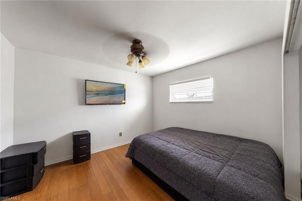 Room featuring wood-finish flooring, a ceiling fan, and a single window with horizontal blinds