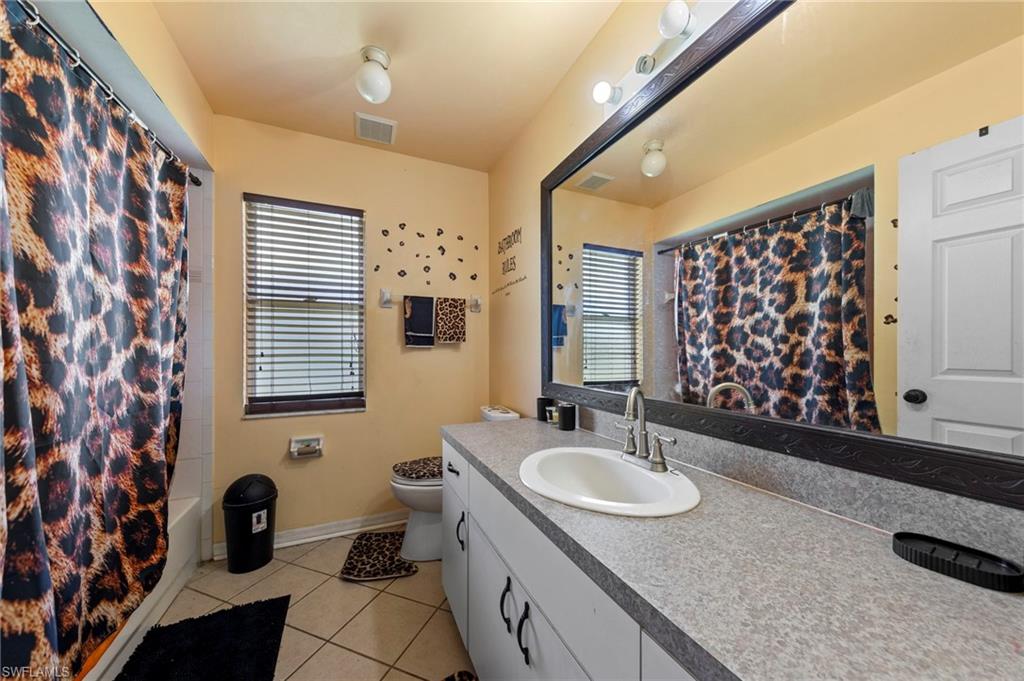 Bathroom featuring a vanity with an integrated sink, a large wall-mounted mirror, and overhead lighting
