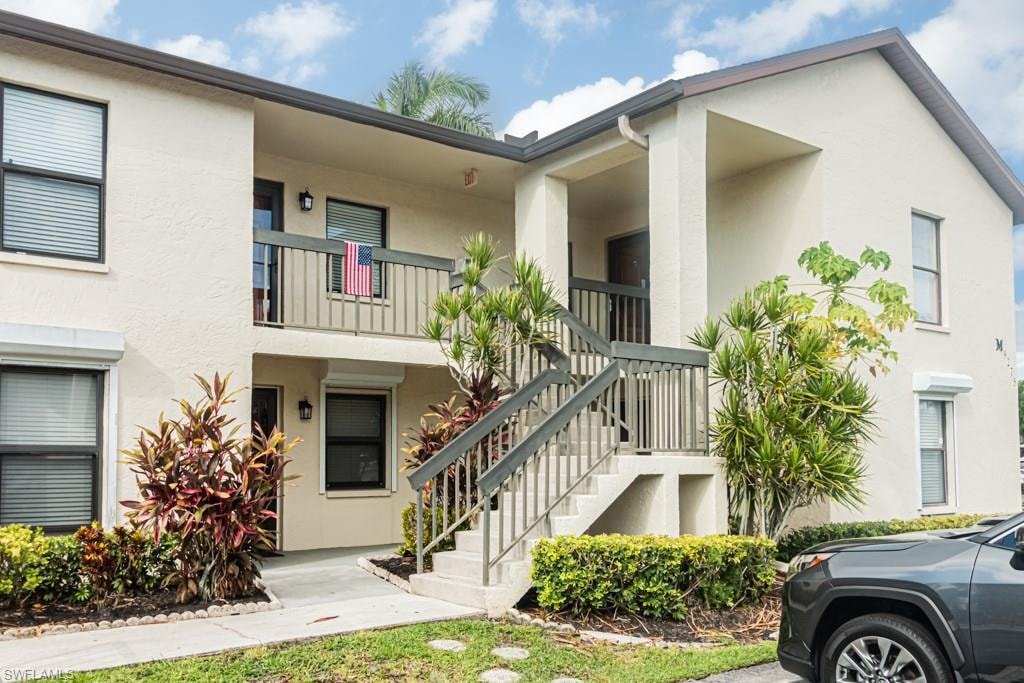 Two-story stucco exterior featuring multiple entrances and a second-story balcony with wood railing