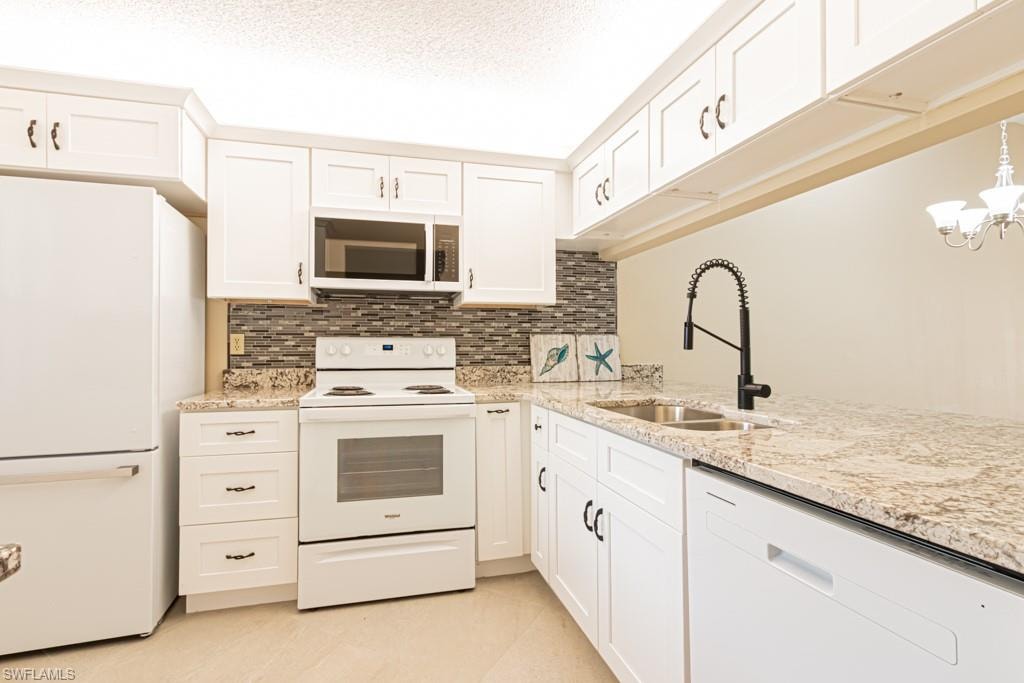 Contemporary kitchen featuring white cabinetry, granite-style countertops, a mosaic tile backsplash, and a modern black faucet