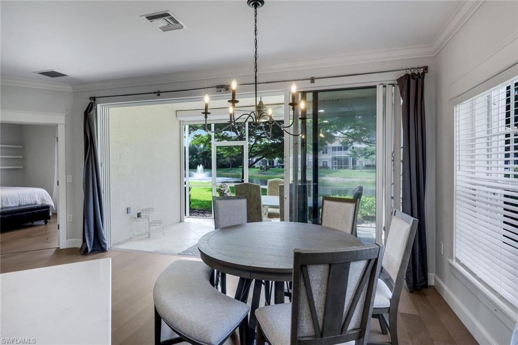 Dining area featuring a contemporary chandelier, LVP flooring, and crown molding
