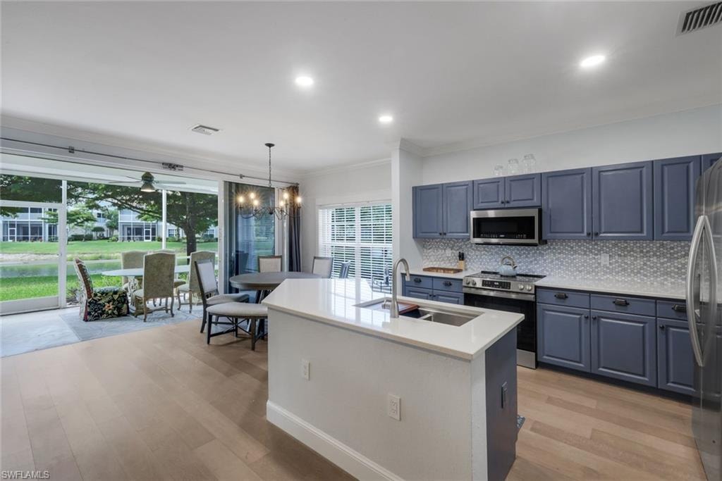 Kitchen featuring a central island with an undermount sink, light-toned LVP flooring, and blue cabinetry