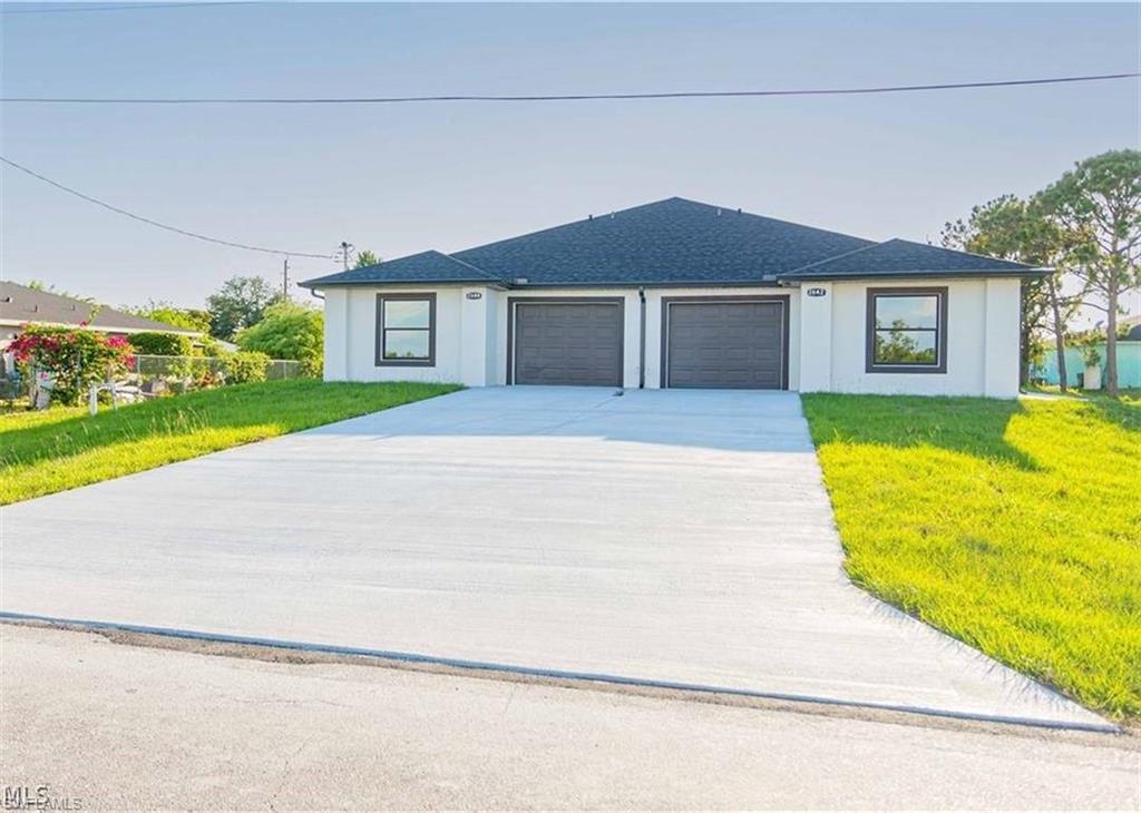 Duplex property featuring a light-toned exterior with dark trim windows and dual single-car garages