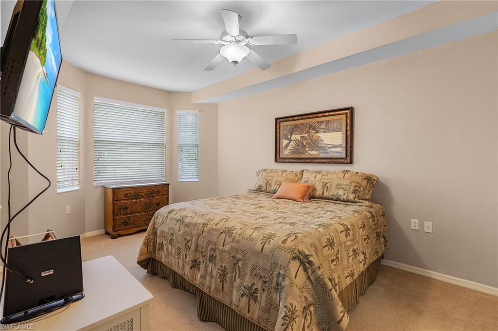 Room featuring neutral wall tones, carpet flooring, a ceiling fan, and multiple windows with blinds
