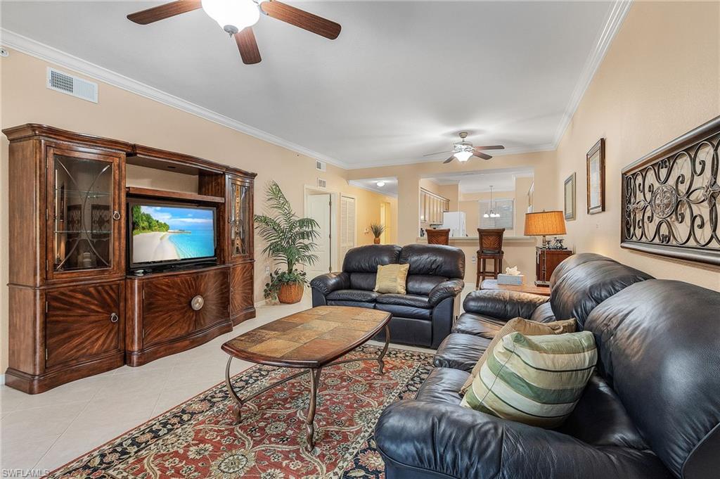 Open-concept living area with crown molding, ceiling fans, and light-toned walls