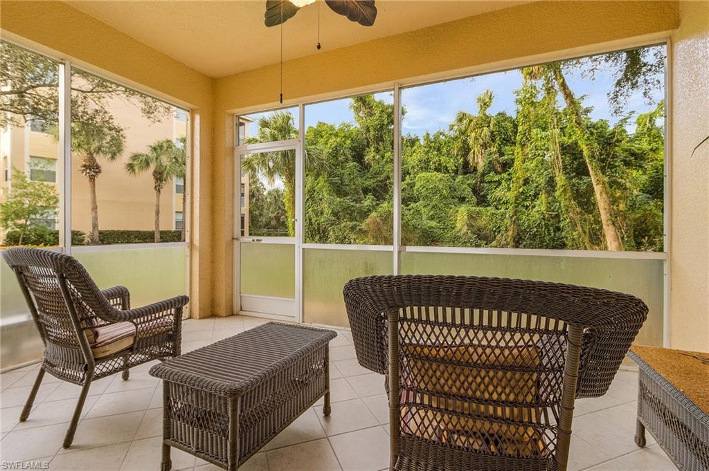 Screened outdoor living area with expansive natural landscape, ceiling fan, and tiled flooring