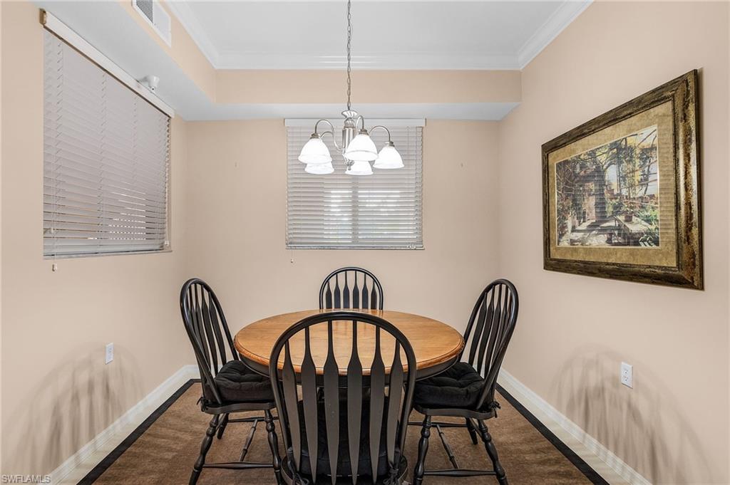 Dining area featuring neutral wall tones, crown molding, and a chandelier lighting fixture