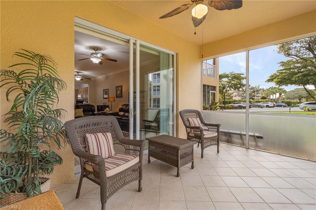Screened balcony featuring a ceiling fan, tiled flooring, sliding glass doors, and textured exterior walls
