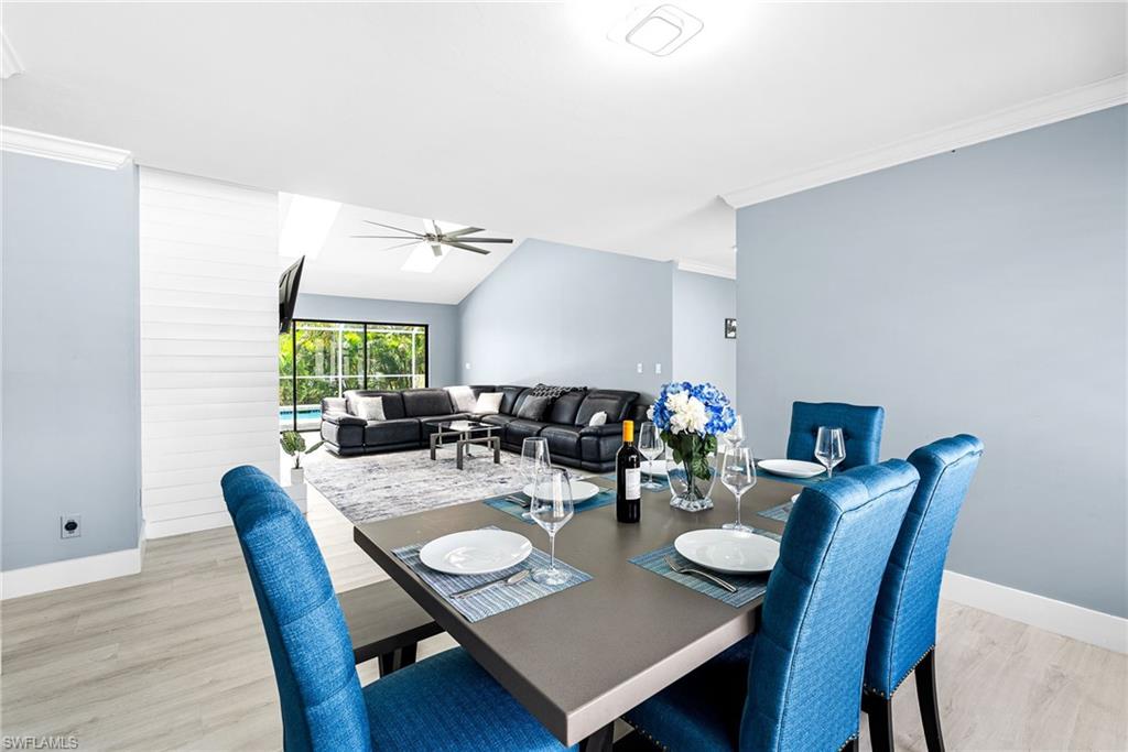 Dining space with ornamental molding, light wood-type flooring, ceiling fan, and lofted ceiling