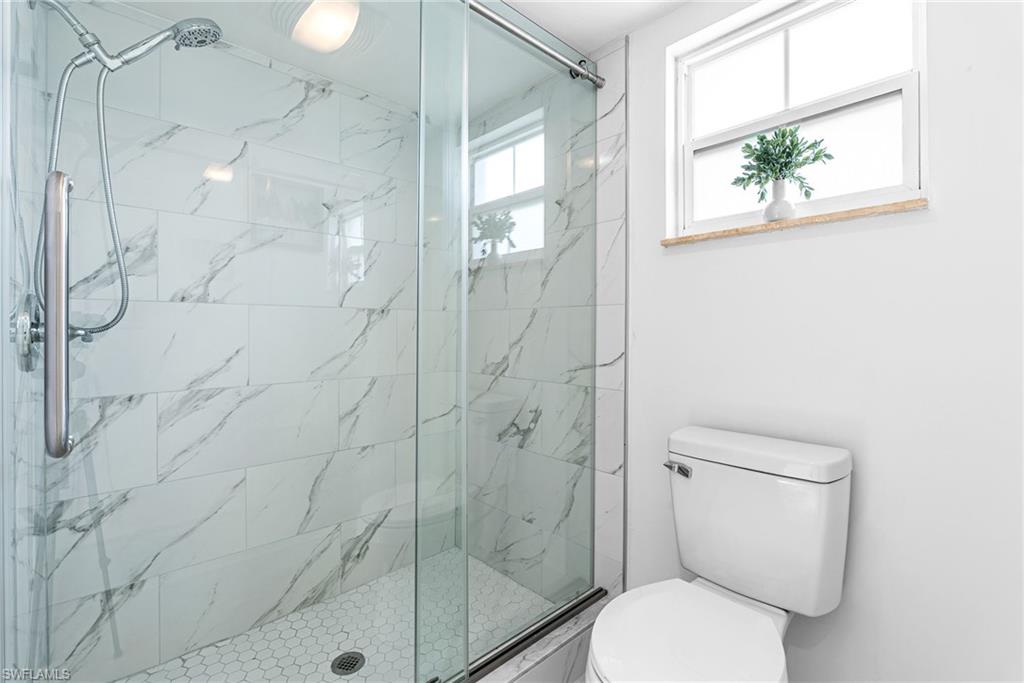 Full bathroom featuring a marble finish shower and toilet