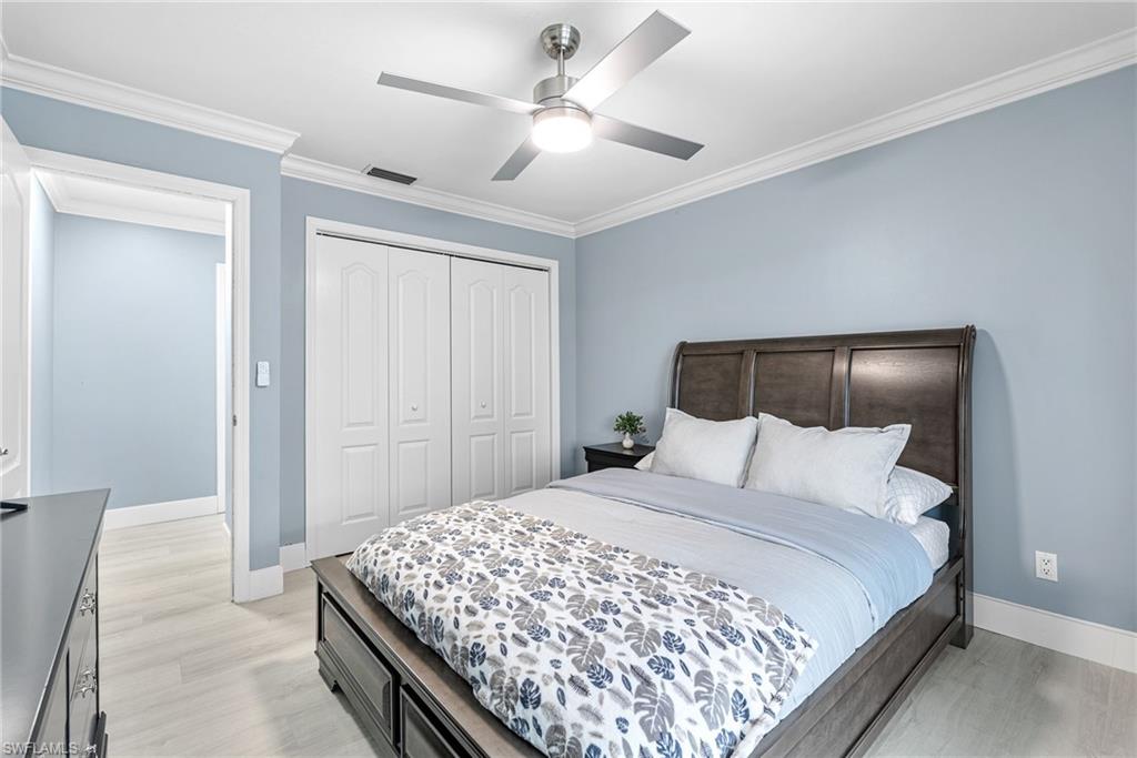 Bedroom featuring ornamental molding, light wood-type flooring, a closet, and ceiling fan