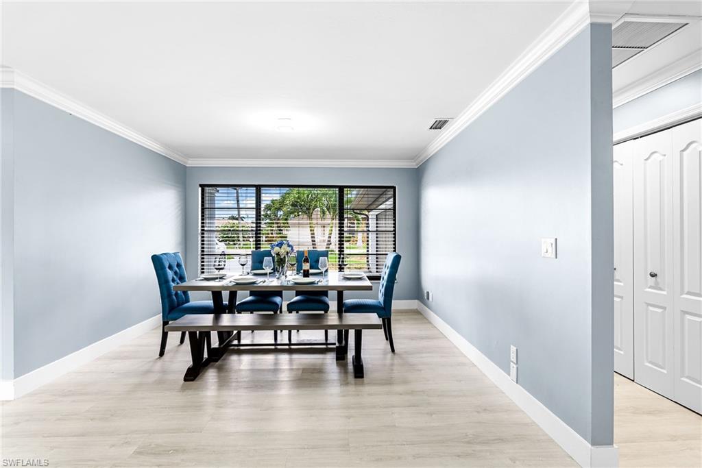 Dining area with ornamental molding and light wood-style flooring