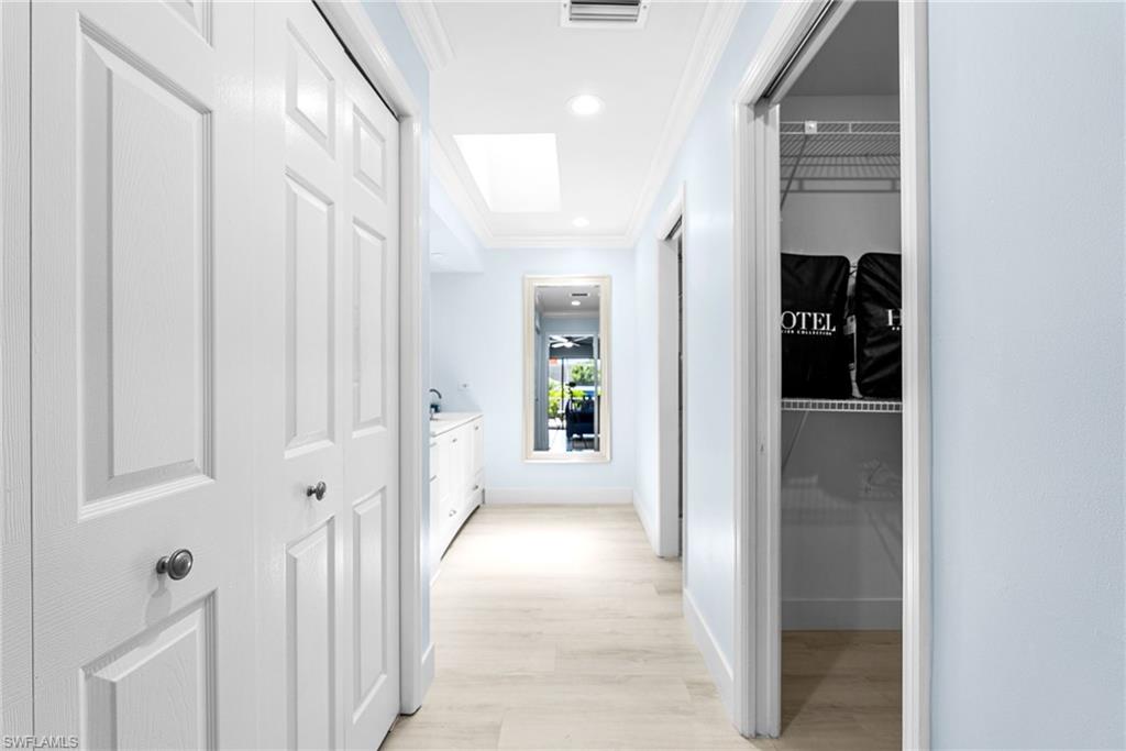 Hallway featuring crown molding, light wood-style floors, and recessed lighting