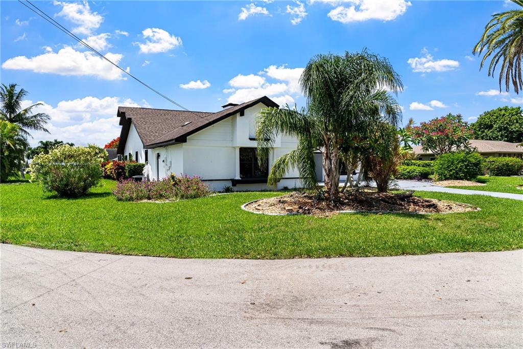 View of front of house with a front yard, stucco siding, driveway, and a shingled roof