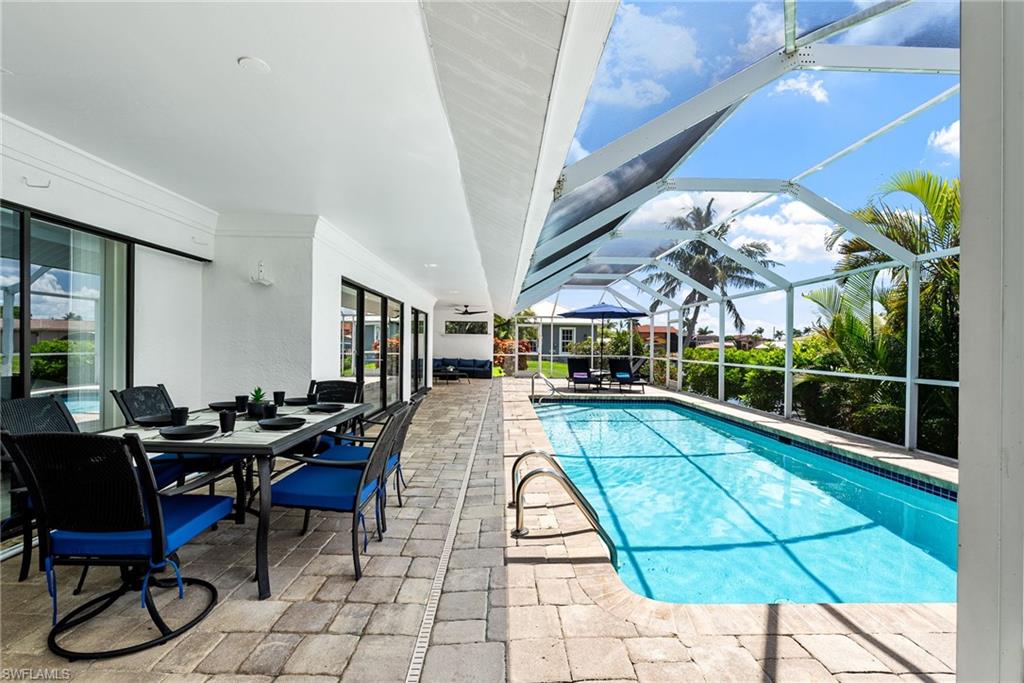 Outdoor pool with a patio, outdoor dining space, a sunroom, and glass enclosure