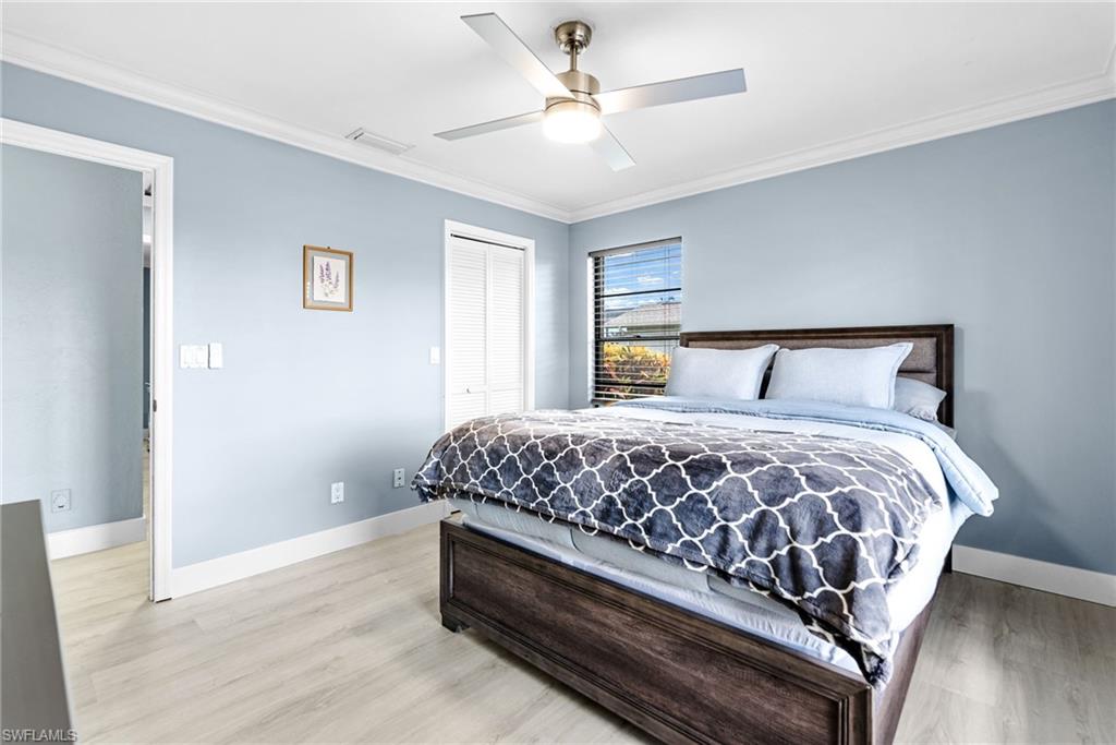Bedroom featuring ornamental molding, a closet, light wood-style flooring, and ceiling fan