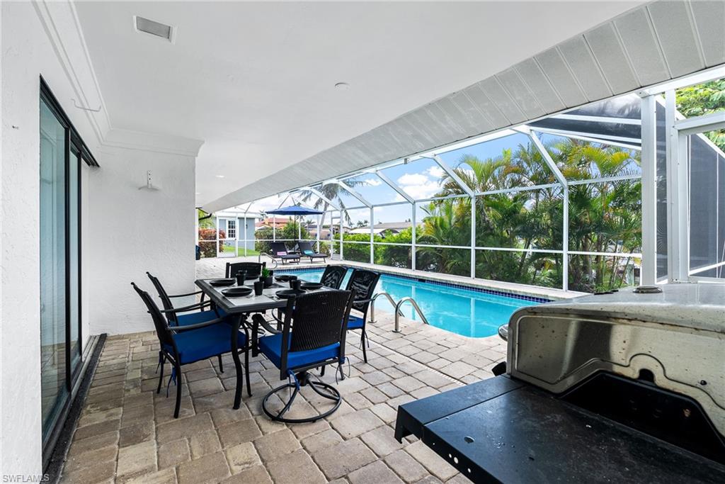 Swimming pool featuring a patio area, glass enclosure, and a sunroom