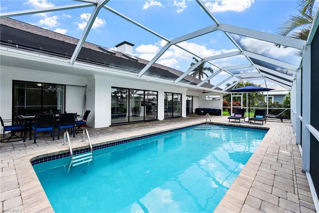 Swimming pool featuring a sunroom, a patio, glass enclosure, and outdoor dining area