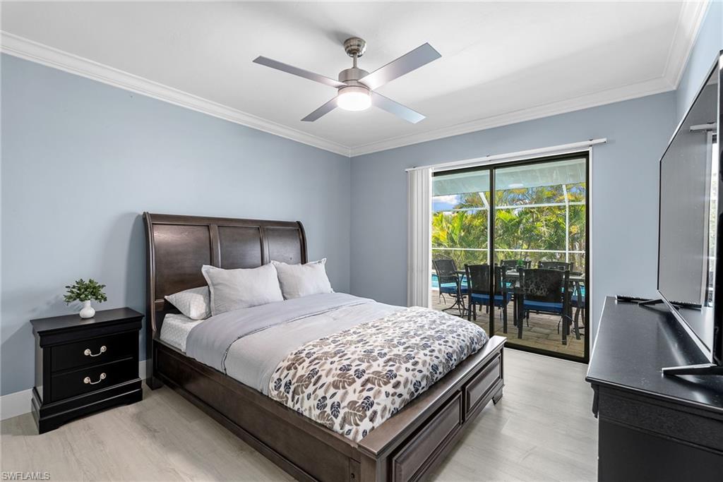 Bedroom with ornamental molding, light wood-type flooring, access to exterior, and a ceiling fan