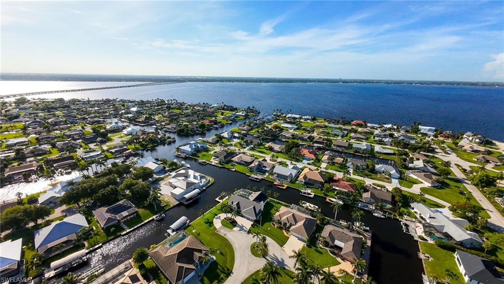 Aerial view of property and surrounding area featuring a nearby body of water and nearby suburban area