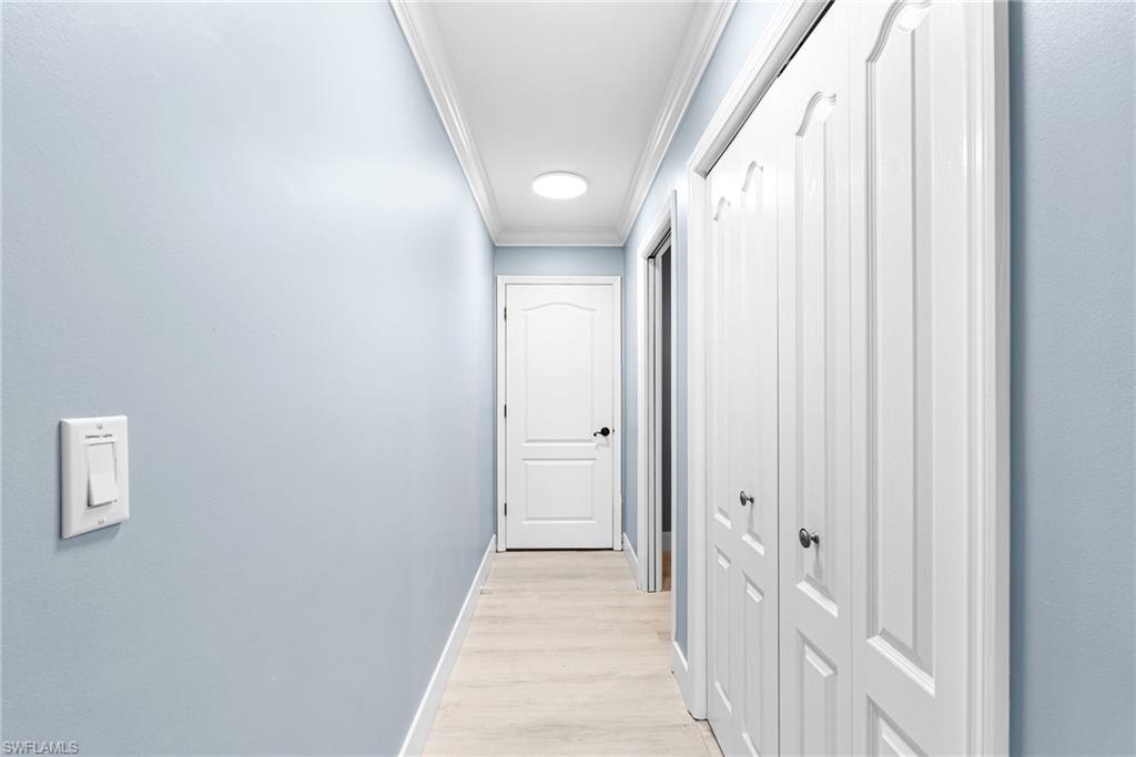 Corridor with ornamental molding and light wood-style floors