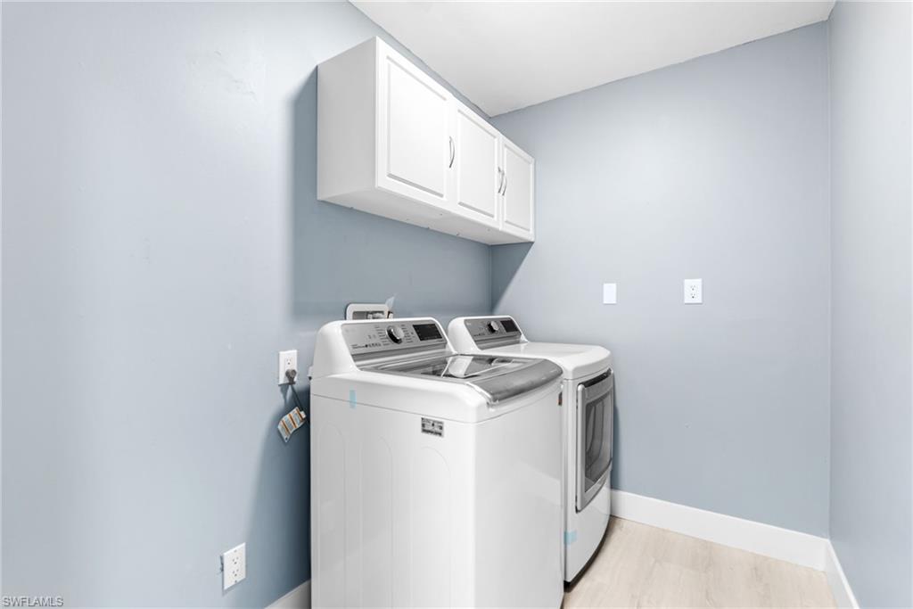 Washroom featuring independent washer and dryer, cabinet space, and light wood-style flooring