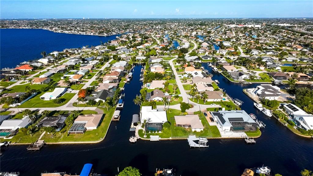 Aerial view of property and surrounding area featuring a nearby body of water and nearby suburban area