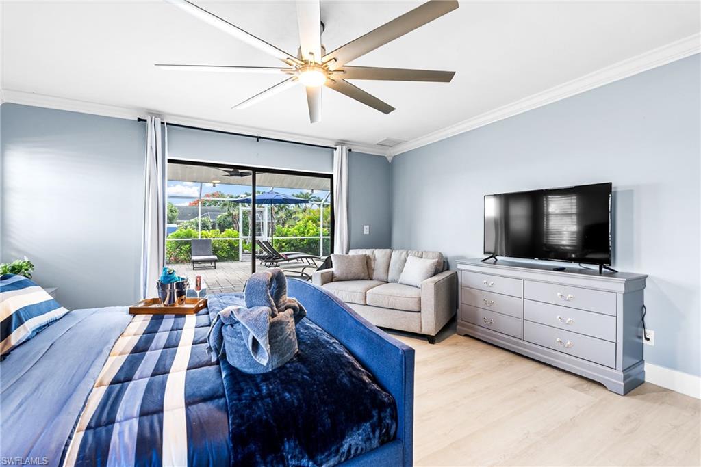 Bedroom with ornamental molding, light wood-style floors, access to exterior, ceiling fan, and floor to ceiling windows