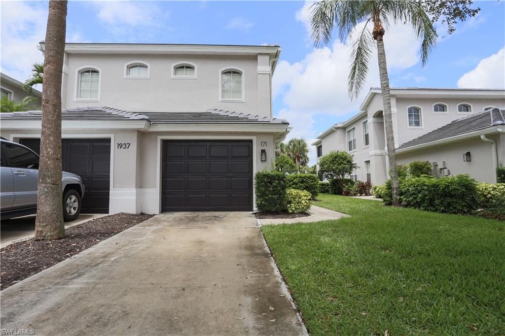 View of front of property with an attached garage, driveway, stucco siding, and a front yard