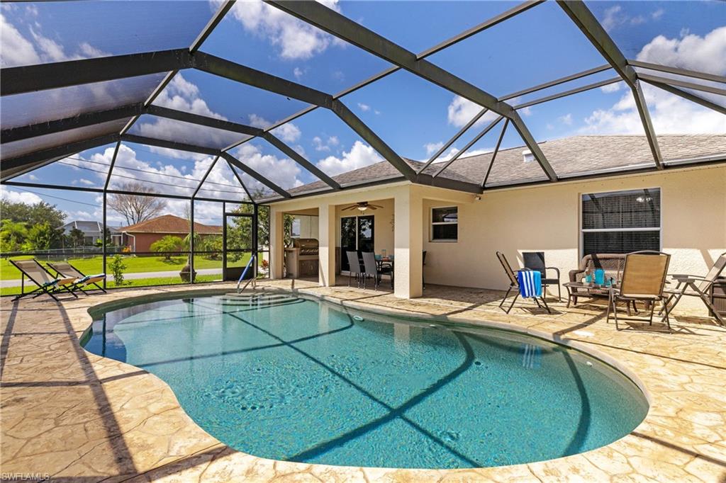 Outdoor pool featuring a patio area, a ceiling fan, and glass enclosure
